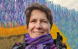 Porträt von Kirsten Elger vor buntem Hintergrund.