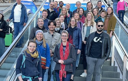 Group photo with 25 people on a staircase at Berlin Central Station.