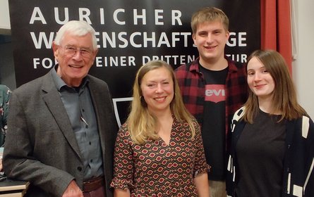 Gruppenfoto mit 4 Personen vor dunkler Wand mit dem Schriftzug Auricher Wissenschaftstage.