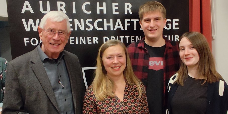 Gruppenfoto mit 4 Personen vor dunkler Wand mit dem Schriftzug Auricher Wissenschaftstage.