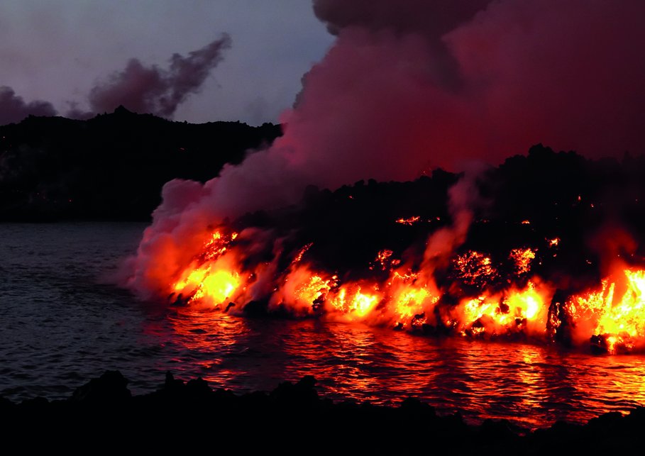 eruption of the Tajogaite volcano on Cumbre Vieja, red hot magma meets the sea, steam billowing around. The night is dark.