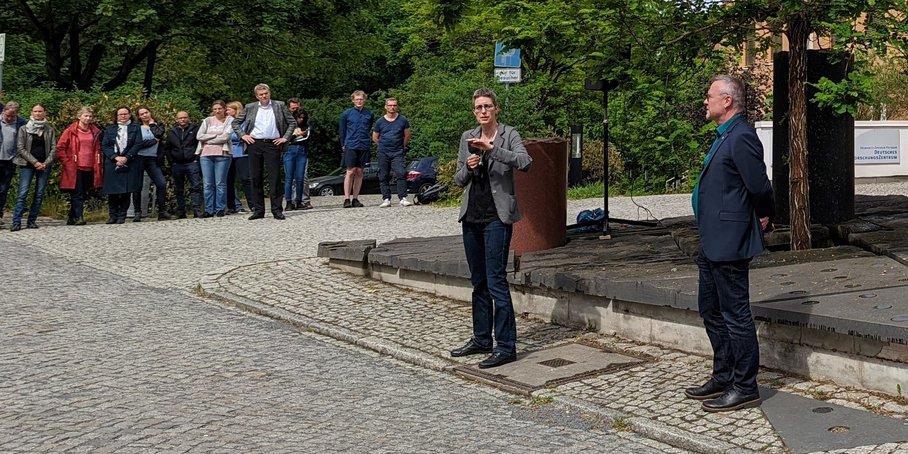 Die neue Vorständin im Interview mit dem Pressesprecher im Kreise der Belegschaft draußen vor dem Gebäude.