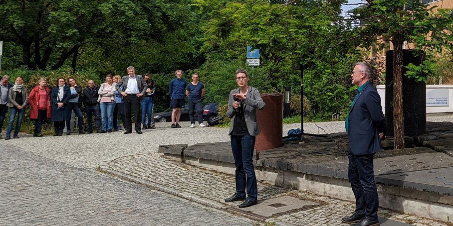 The new director in an interview with the press spokesperson in the circle of staff outside the building.