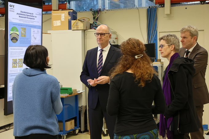 5 persons standing in front of a scientific poster in a lab.