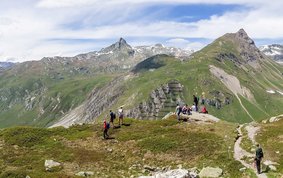 Typische Gebirgslandschaft der Alpen: Spitze, felsige Berge, im Vordergrund noch grün bewachsen, im Hintergrund zum Teil mit Schnee bedeckt.