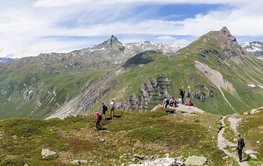 Typische Gebirgslandschaft der Alpen: Spitze, felsige Berge, im Vordergrund noch grün bewachsen, im Hintergrund zum Teil mit Schnee bedeckt.