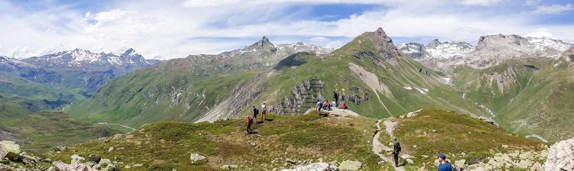 Typische Gebirgslandschaft der Alpen: Spitze, felsige Berge, im Vordergrund noch grün bewachsen, im Hintergrund zum Teil mit Schnee bedeckt.