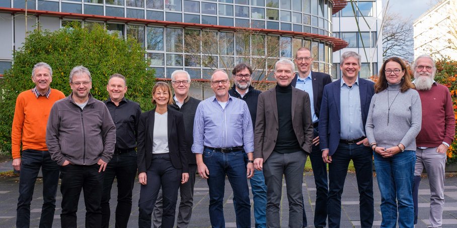 Group photo of 12 people in front of a DFN building.