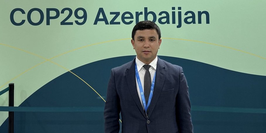 [Translate to English:] Abror Gafurov von dem Schriftzug "Welcome to Azerbaijan" und den UN und COP Logos