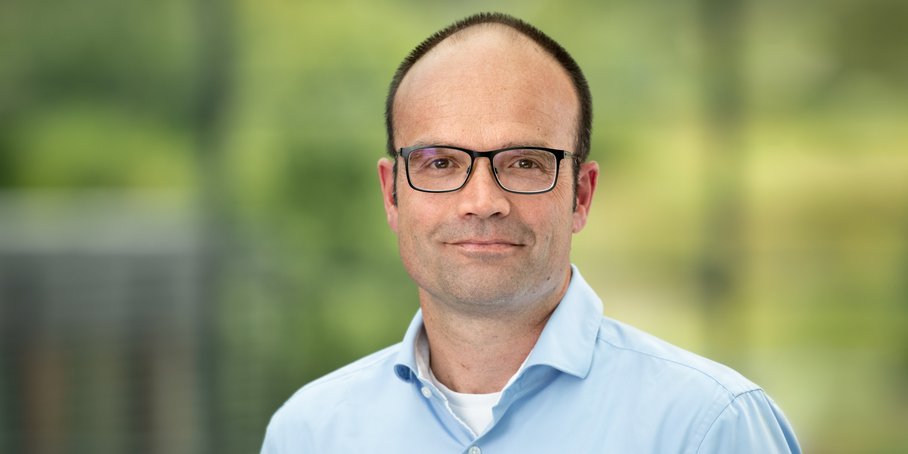Portrait Lars Bernard vor grünem verschwommenen Hintergrund
