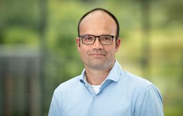 Portrait Lars Bernard vor grünem verschwommenen Hintergrund