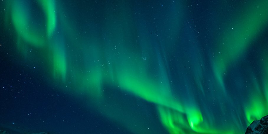Green aurora borealis, in the bottom right corner mountain peak