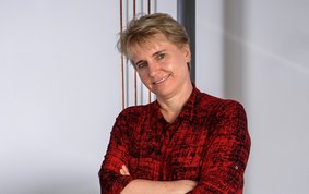 Profile of Prof. Dr. Liane G. Benning, with short blonde hair, red shirt and content face expression.