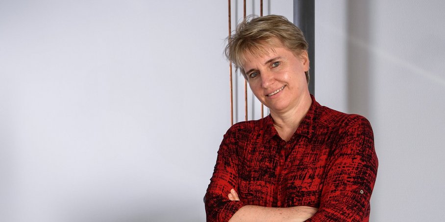 Profile of Prof. Dr. Liane G. Benning, with short blonde hair, red shirt and content face expression.