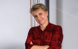 Profil von Prof. Dr. Liane G. Benning, mit kurzen blonden Haaren, rotem Oberteil und Lächelndem Blick