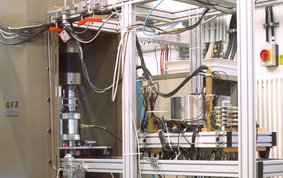 Mensch-hohes metallisches Gestell mit metallischen Zylindern und bunter Verkabelung.