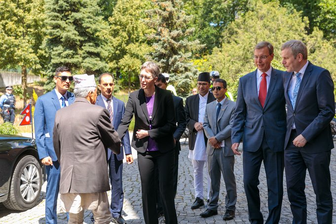 An old man shakes the hand of a woman. Other people are standing next to him.