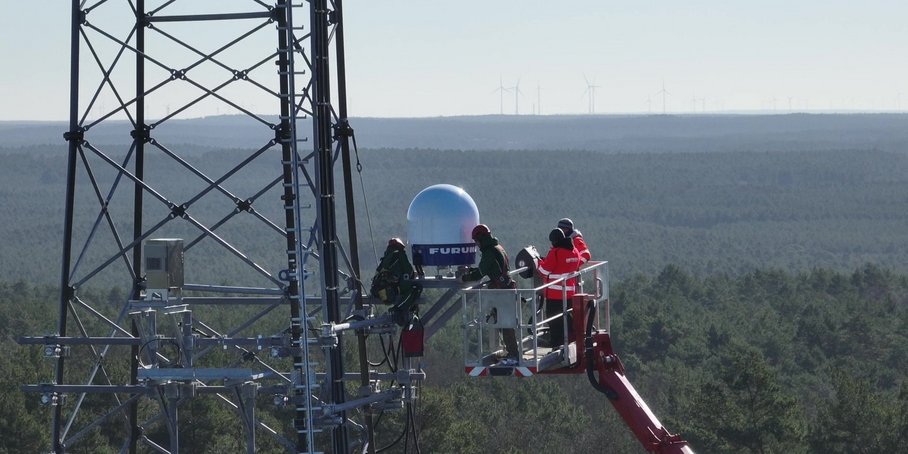 Close-up of radar installation on the radio tower, with person in red climbing gear