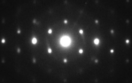 Weiße Punkte unterschhiedlicher Dicke in hexagonalem Muster auf schwarzem Grund.