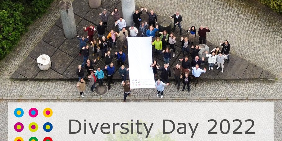 A group of people gathering around the flag for Diversity Day - in the pillar forum on Telegrafenberg.