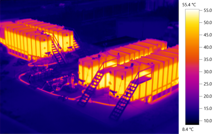 Wärmebild von vier Containern: Die warmen Container und einige verbindende Rohre sind rot-orange, die kühlere Umgebung ist blau.