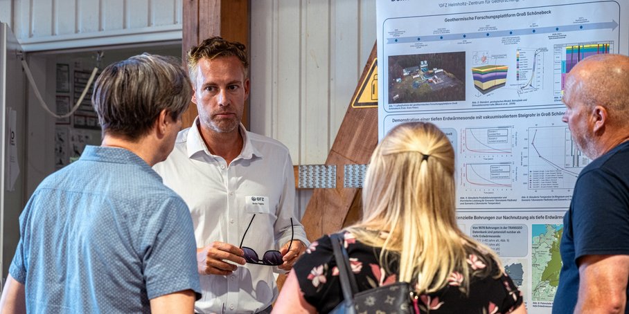 Vor einer Wand mit wissenschaftlichem Postern stehen vier Personen und diskutieren