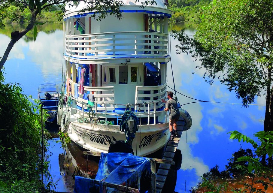 A white boat among tree rows aside a river.