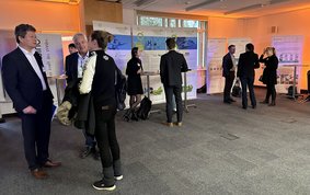 Posterausstellung auf dem Brandenburgischen Wasserstofftag am GFZ, einige teilnehmende Personen im Vordergrund