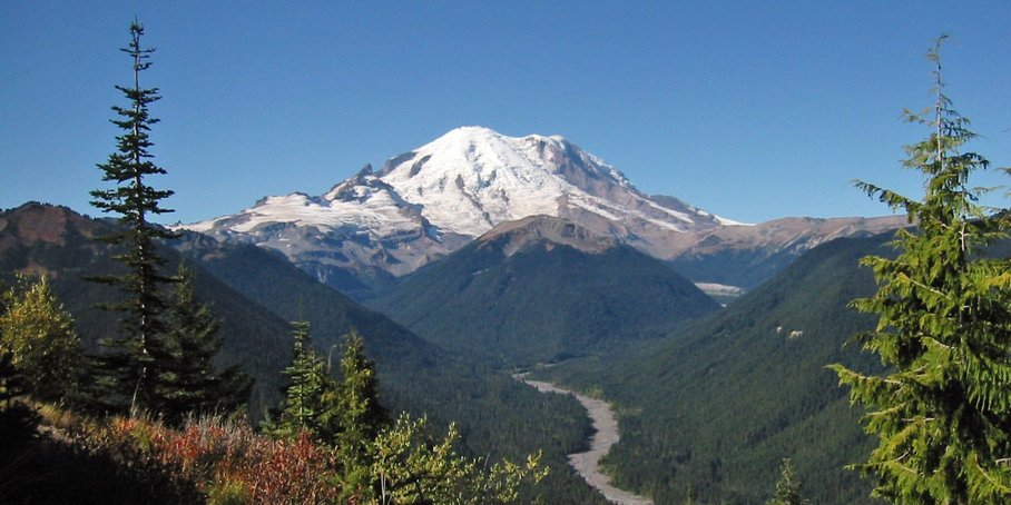 schneebedeckter gebirgsähnlicher Vulkan inmitten eines Naturlandschaft mit Wasserstrom im Tal