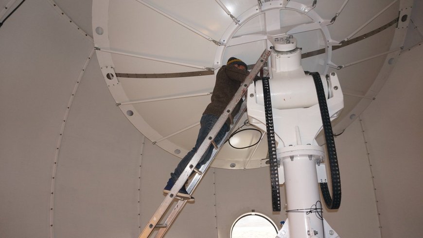 The photo shows a GFZ-technician on a ladder leaning in a radome at one of the antennas.