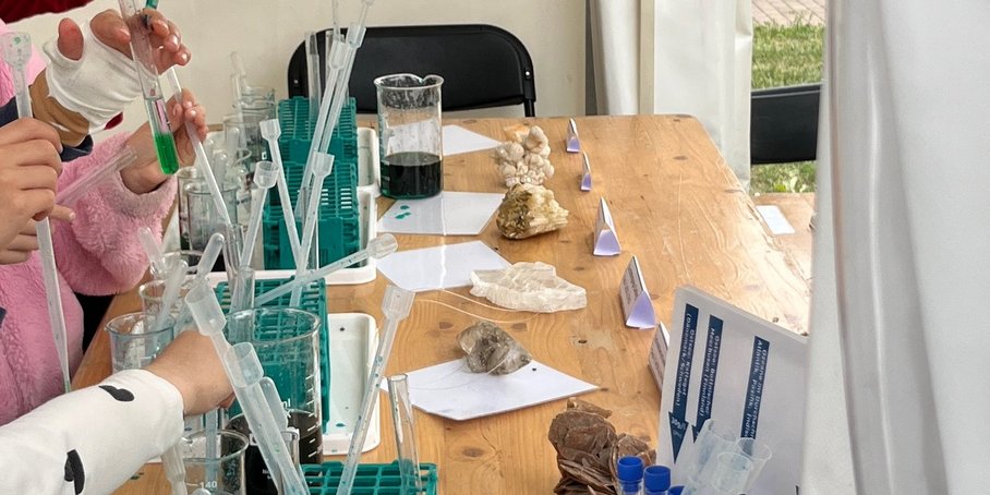 Kinderhände arbeiten mit Pipetten und versuchen Wasser im Reagenzglas zu stapeln