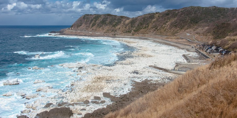 A steep coastline by the sea. The area in front of the steep coastline has apparently been raised, as the ground that used to lie under the sea now lies above the water surface.