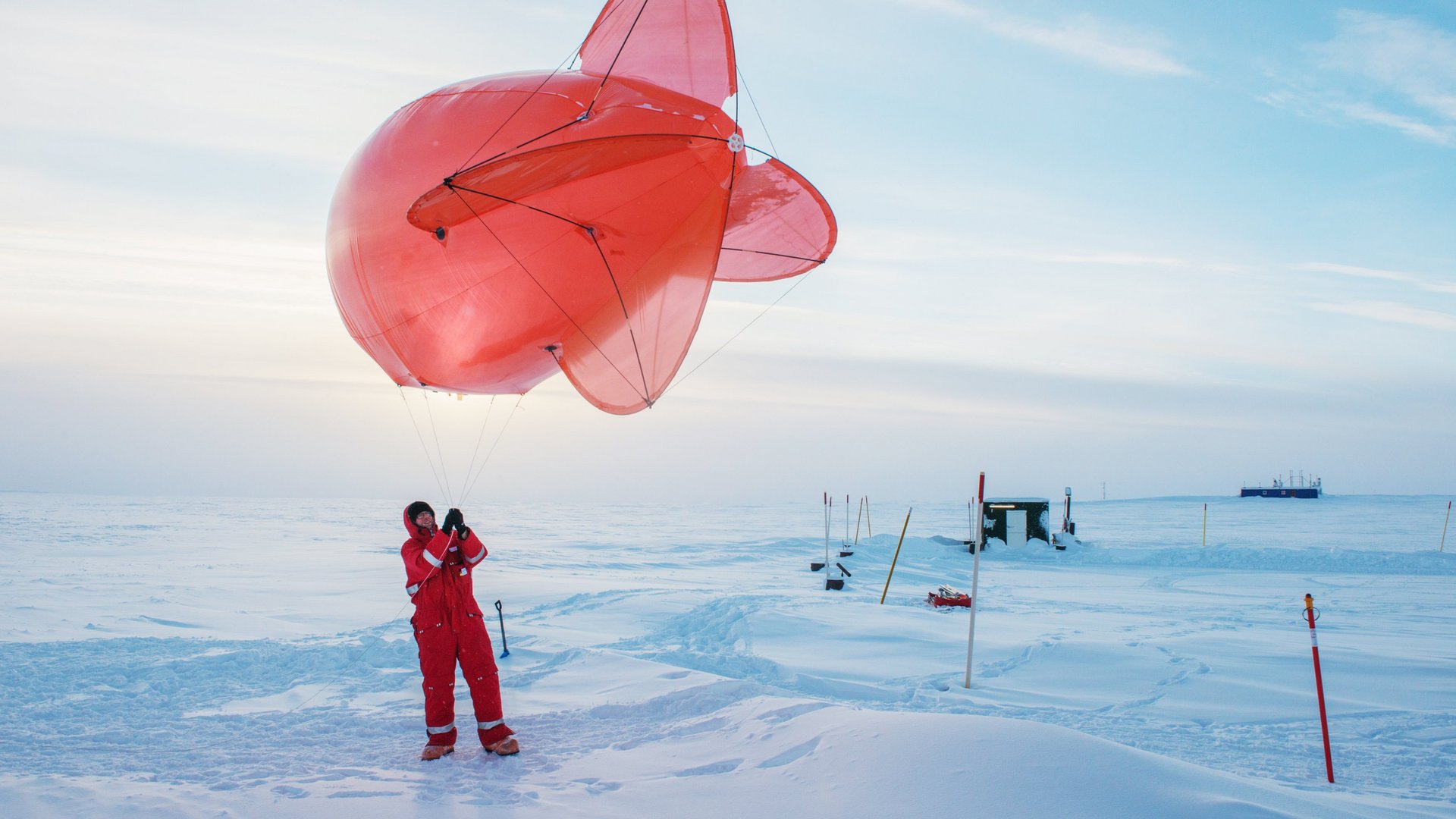 Foschungsballon rot in Eislandschaft gehalten von einem Forscher