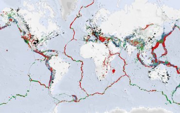 World map: Sea light blue, continents white. Short lines in bright colours indicate the direction of the greatest horizontal tension at many points, especially along plate boundaries, with many points in Central America and South-Eastern Europe/Turkey.