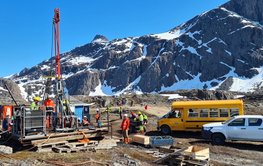 Bohrung auf Grönland. Berge, Schnee und Fels und Personen sind zu sehen