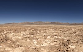 Desert landscape with hills and a dry lake bed.