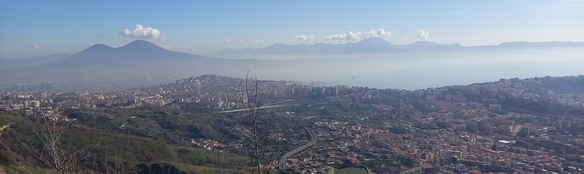 Städtisches Gebiet am Fuße eines Berges, im Hintergrund weitere Berge und das Meer.