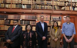 Gruppenfoto mit 5 Personen vor der Bücherwand einer historischen Bibliothek.