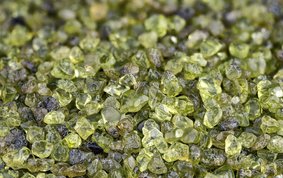 Nahaufnahme eines Bettes aus grünen kantigen Olivin-Kristalle