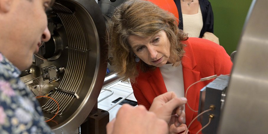 Nahaufnahme einer Frau, die in das Innere einer Labor-Maschine blickt.