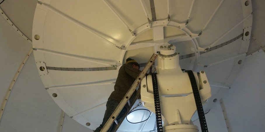 Eine Person im inneren der weißen Kuppel schraubt Apparaturen fest.