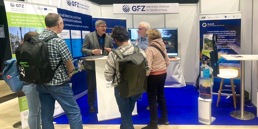 Eiin Messestand mit Bildschirmen, Postern und mehreren Besuchern.