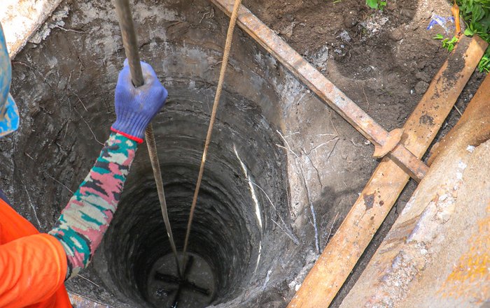 Mann mit Helm über einem Bohrloch