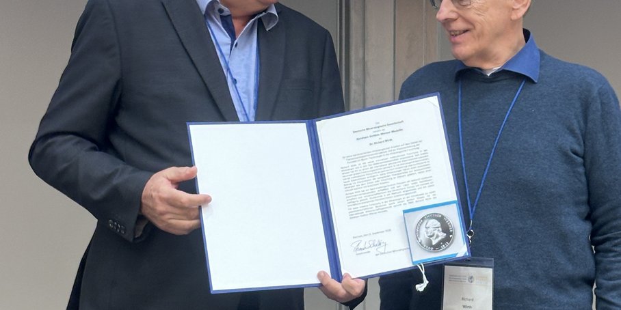 Dr. Wirth wird die silberne Medallie in einer Mappe überreicht.