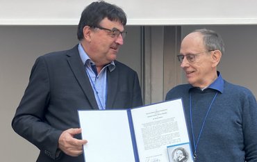 Dr. Wirth wird die silberne Medallie in einer Mappe überreicht.