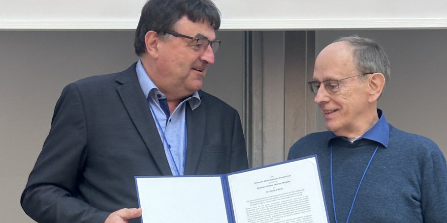Dr. Wirth wird die silberne Medallie in einer Mappe überreicht.